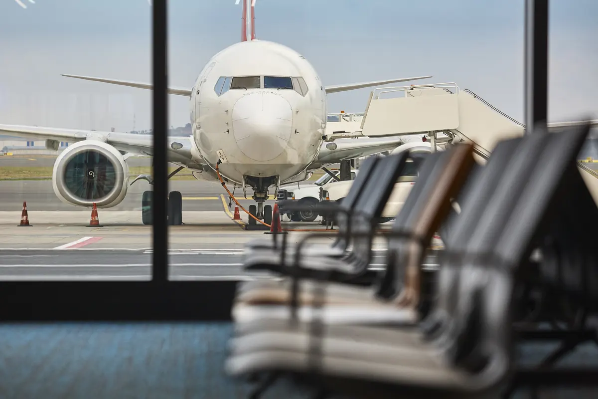 Avión estacionado visto desde una sala de embarque vacía